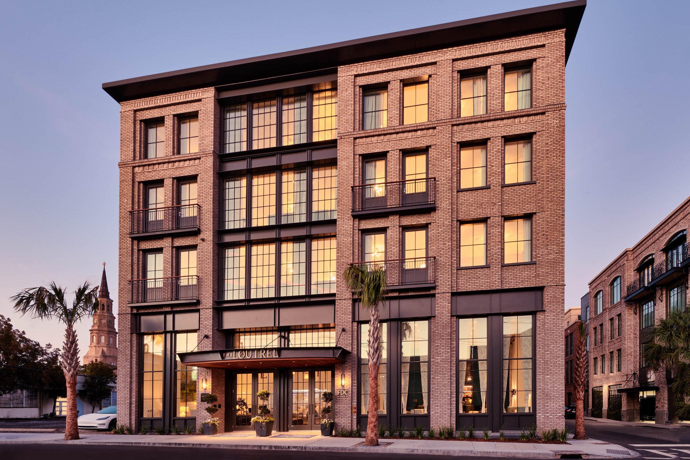 A brick hotel in Charleston at dusk, its windows lit